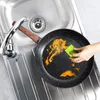 A hand is cleaning a frying pan in a kitchen sink. Produktbild-Vorschau