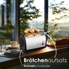 A toaster with bread and rolls on a kitchen counter next to a window with a view of nature. Produktbild-Vorschau
