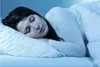 A woman sleeping peacefully in bed, covered by a white duvet. Produktbild-Vorschau