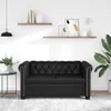 A black Chesterfield sofa is shown in a well-lit room with shelves on the wall. Produktbild-Vorschau