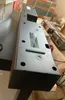 The underside of a black soundbar is shown in a close-up shot, with some boxes and other items in the background. Voir les images du produit