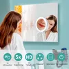 A woman in a bathrobe is looking into a large mirror, with a smaller illuminated magnifying mirror attached to it showing her face. Produktbild-Vorschau