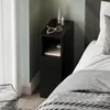 A black bedside table next to a bed, with a curtain and a basket in the foreground. Produktbild-Vorschau