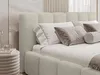 A close-up view of a bed with beige bouclé fabric, featuring pillows and a throw blanket. Náhled obrázku produktu