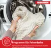Hands holding a white knitted garment in front of an open washing machine drum. Produktbild-Vorschau