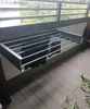 A wall-mounted drying rack with clothes hanging on it, on a balcony. Voir les images du produit