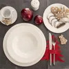 A Christmas-themed table setting with plates, cutlery, candles, and cookies. Voir les images du produit