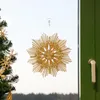 A straw star ornament hangs in a window next to a Christmas tree. Produktbild-Vorschau