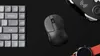 A flat lay of computer peripherals including a keyboard, mouse, and smartwatch on a black surface. Produktbild-Vorschau