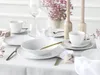 A beautifully set dining table with white porcelain tableware, gold cutlery, and pink flowers. Náhľad obrázku produktu