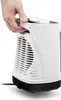 A hand is holding the handle of a white and black electric heater. Podgląd zdjęcia produktu