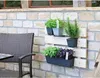 A vertical planter with herbs mounted on a brick wall next to a chair. Voir les images du produit
