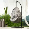 An outdoor scene with a hanging chair, plants, and a scenic background. Náhled obrázku produktu