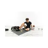 A man sitting on a yoga mat after a workout, with sports equipment around him. Produktbild-Vorschau