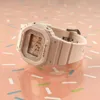 A light pink Casio Baby-G watch is displayed on a pink surface with colorful sprinkles. Podgląd zdjęcia produktu