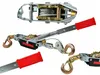 Multiple views of a hand winch, also known as a cable puller or come-along, are shown against a white background. The winch features a metal body, a steel cable, and red rubber grips on the handles. Náhled obrázku produktu