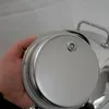 A hand holding the lid of a stainless steel container. Produktbild-Vorschau