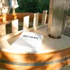 A wooden hot tub with a towel on top, set outdoors. Produktbild-Vorschau