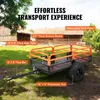 A trailer is parked in a grassy area with buildings in the background. Produktbild-Vorschau
