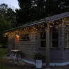 A wooden shed decorated with warm white LED string lights along the roofline. Podgląd zdjęcia produktu