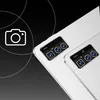 A close-up marketing image of the rear camera module of two white tablets, with a stylized camera icon and circular graphic elements in the background. Podgląd zdjęcia produktu