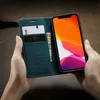Hands holding a teal leather iPhone case with cards and cash inserted, and an iPhone with a colorful wallpaper. Produktbild-Vorschau