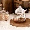 A honey jar with a dipper on a wooden tray, next to a jar of sugar. Náhľad obrázku produktu
