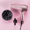 A pink hairdryer and its attachments are laid out on a pink background. Voir les images du produit