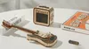 A wooden model of an electric guitar and amplifier are displayed on a white surface, with two books in the background. Voir les images du produit