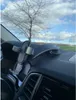 A car dashboard with a phone holder mounted on it, with a tree and sky visible through the windshield. Anteprima dell’immagine prodotto