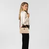 A woman is modeling a beige handbag. Produktbild-Vorschau