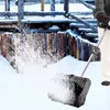 A person is using a snow blower in a snowy environment with wooden structures in the background. Produktbild-Vorschau