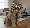 A decorative lion figurine with dreadlocks, headphones, and sunglasses sits in a living room setting. Produktbild-Vorschau