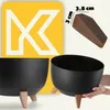 A product image featuring two black planters with wooden legs, a close-up of a brown wedge with dimensions, and a large yellow graphic with a white 'K' logo. Produktbild-Vorschau