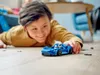 A child is playing with a blue LEGO car on the floor. Podgląd zdjęcia produktu