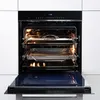 An open built-in oven with racks and trays inside, showing the interior heating elements. Produktbild-Vorschau