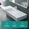A modern white washbasin with a sleek design, mounted on a dark green pedestal, with a large illuminated mirror reflecting a toilet and a bathtub in the background. The bottom of the image features a teal overlay with icons and text highlighting product fe Produktbild-Vorschau