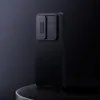 A black phone case with a textured surface and a sliding camera cover is displayed on a dark, reflective surface against a dark background. Produktbild-Vorschau