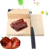 A meat slicer with a wooden base and metal blade, shown with sliced meat. Náhled obrázku produktu