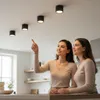 Two women in a modern kitchen setting, one pointing towards ceiling lights. Podgląd zdjęcia produktu