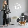 A woman is leaving her home, and an automatic cat litter box is visible with a cat nearby. Podgląd zdjęcia produktu