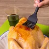 A person is basting a whole chicken with a brush. Produktbild-Vorschau