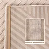 A close-up view of the underside of a rug, showing its natural jute bottom and a woven striped pattern. Produktbild-Vorschau