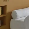 A white bolster pillow on a white bed against a tan wall. Produktbild-Vorschau