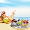 A woman is relaxing on a beach, drinking from a coconut, with an inflatable drink tray floating nearby. Náhled obrázku produktu