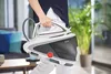 A person holds a Tefal Pro Express steam generator iron in a living room setting. Produktbild-Vorschau