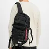 A person wearing a long-sleeved shirt and a black tactical backpack. Produktbild-Vorschau