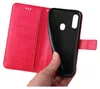 A hand holding a red flip phone case with floral and butterfly embossing. Produktbild-Vorschau