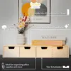 A wooden drawer unit with books and flowers on top, displayed against a wall with artwork. Náhled obrázku produktu