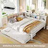 A daybed with a pull-out trundle bed, set up in a bright room with large windows, featuring a headboard with integrated shelving and charging ports. Produktbild-Vorschau